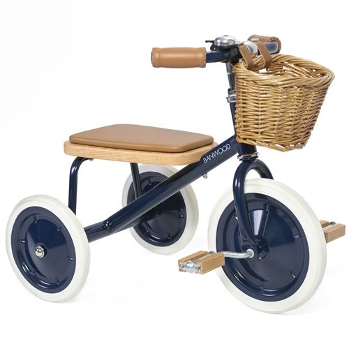 Banwood blauwe driewieler met bruin zadel, pedalen en mandje, schuin van voren gezien.