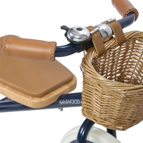 Detail van het stuur van de Banwood driewieler met bruine handvatten, bel en rieten mandje.