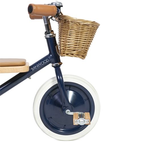 Detail van het voorwiel van de Banwood driewieler met houten pedalen en rieten mandje.