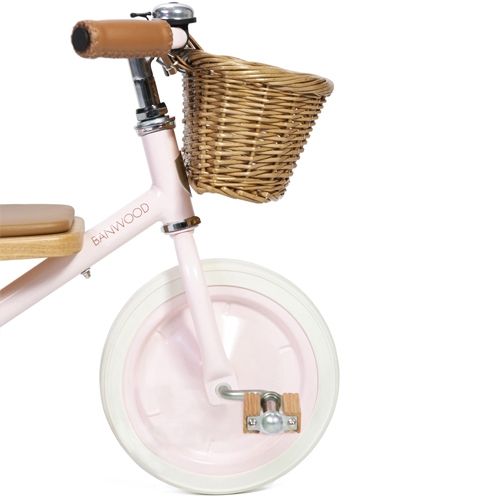 Detail van het voorwiel en de houten pedalen van de Banwood roze driewieler met rotan mandje.