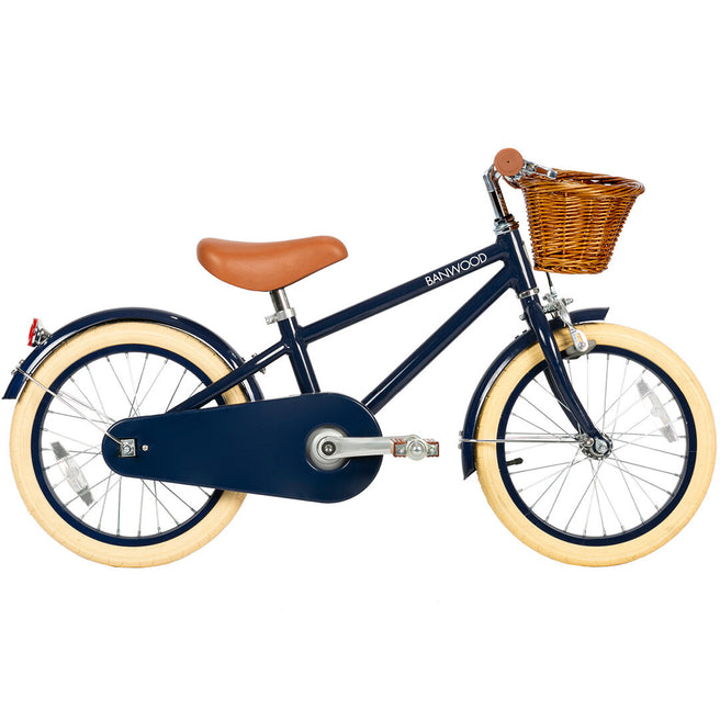 Banwood kinderfiets in donkerblauw met bruin zadel, crèmekleurige banden en een rieten mandje, van de zijkant.