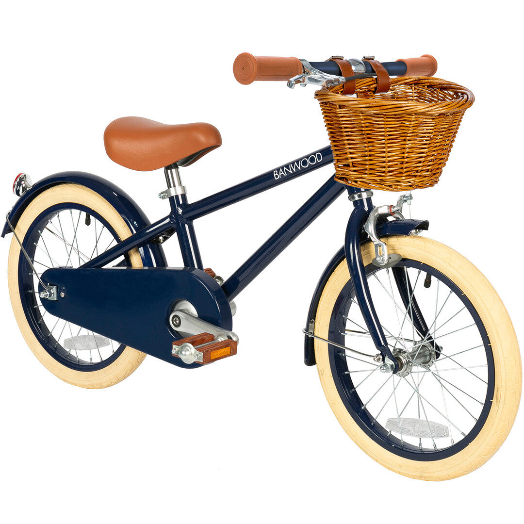 Banwood kinderfiets in donkerblauw met bruin zadel, crèmekleurige banden en een rieten mandje, schuin van voren.