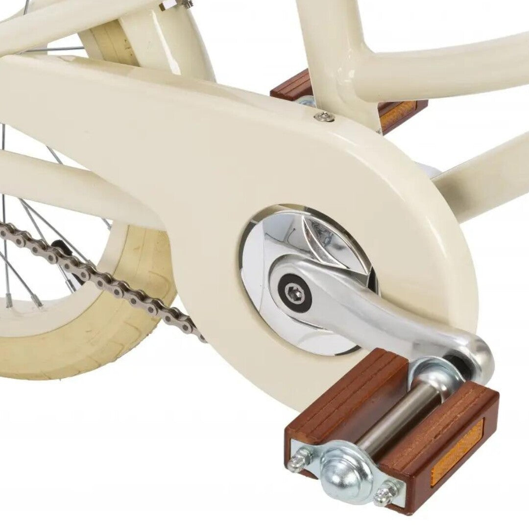 Detail van de houten pedalen en crèmekleurige kettingkast van de Banwood kinderfiets.