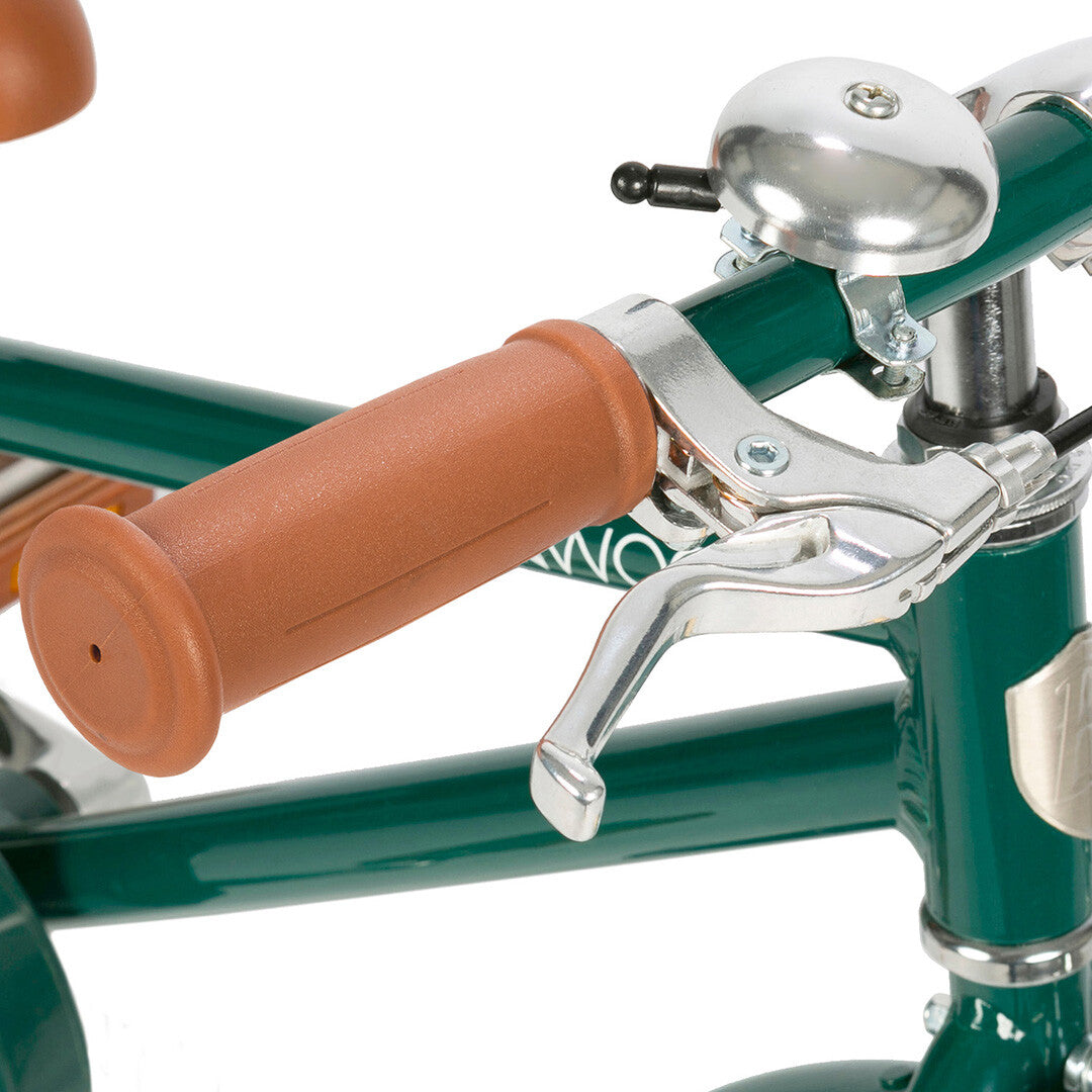 Detail van het stuur van de groene kinderfiets met bruine handgreep, zilveren rem en bel.