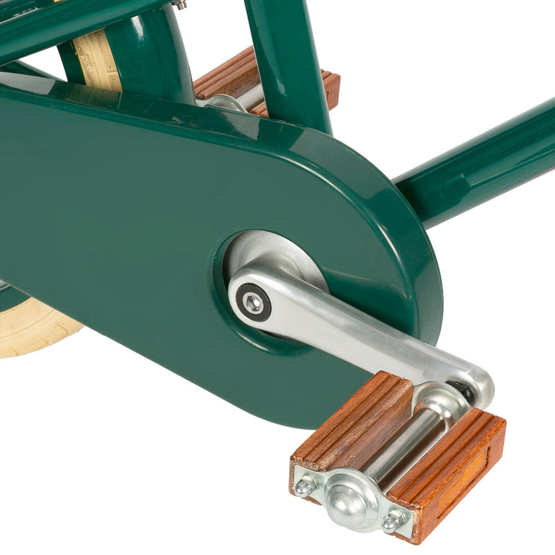 Detail van de houten pedalen en de groene kettingkast van de kinderfiets.