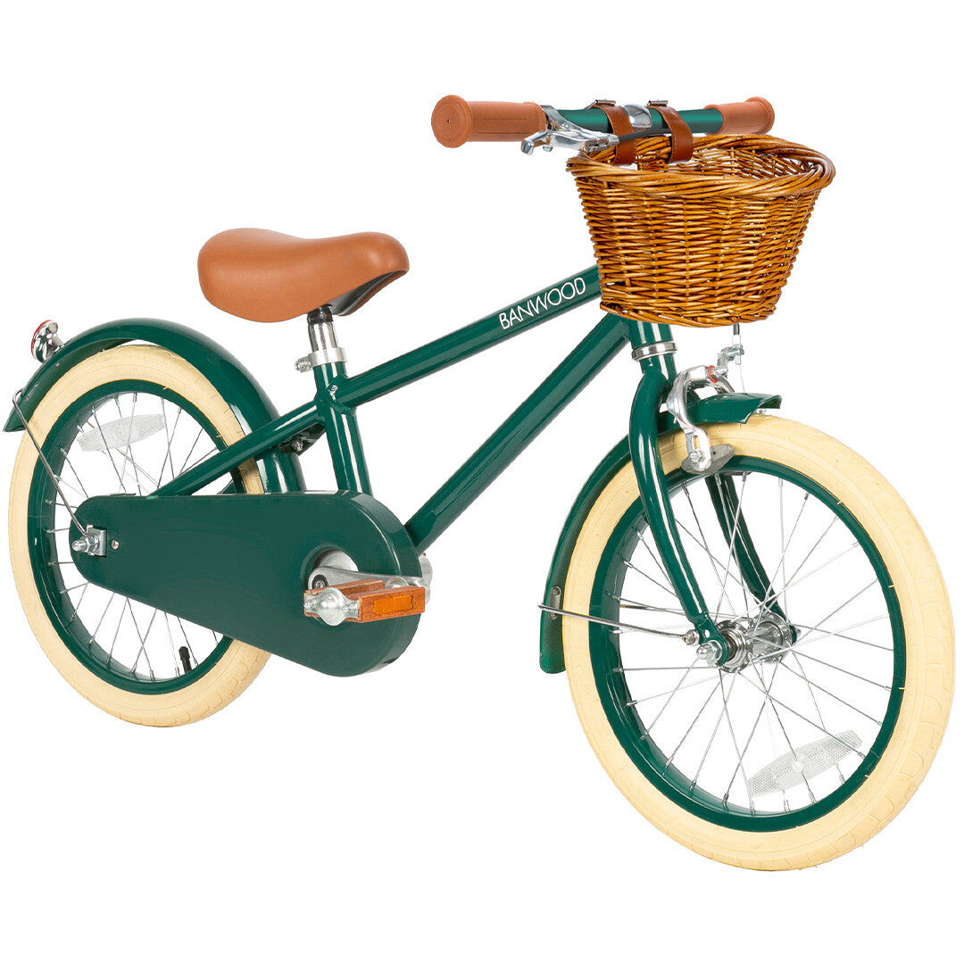 Banwood groene kinderfiets met bruin zadel, crèmekleurige banden en rieten mand, schuin van voren gezien.
