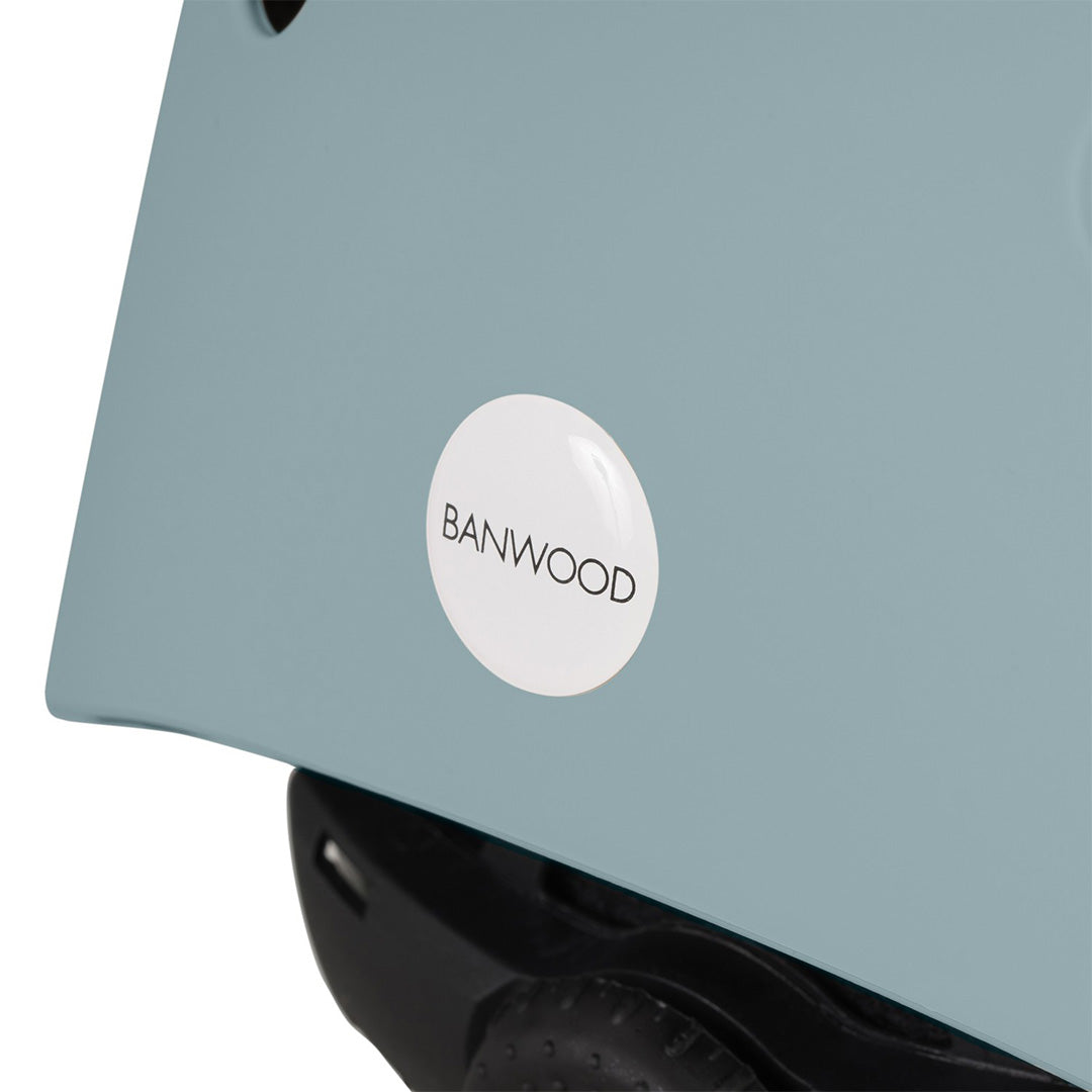 Detail van de lichtblauwe Banwood kinderhelm met ronde merksticker op de zijkant.