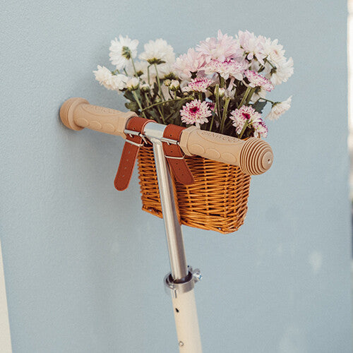 Detail van het stuur van een Banwood kinderstep maxi met een rieten mandje vol bloemen.