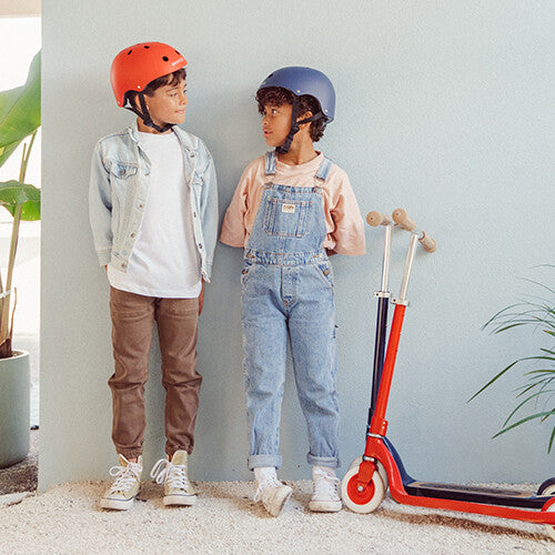 Twee kinderen met helmen staan naast een rode Banwood kinderstep.