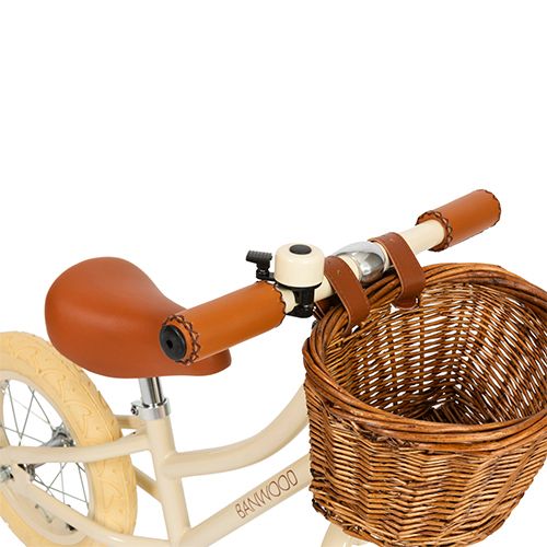 Detail van het stuur en zadel van de Banwood loopfiets met bruine accenten en een rotan mandje.