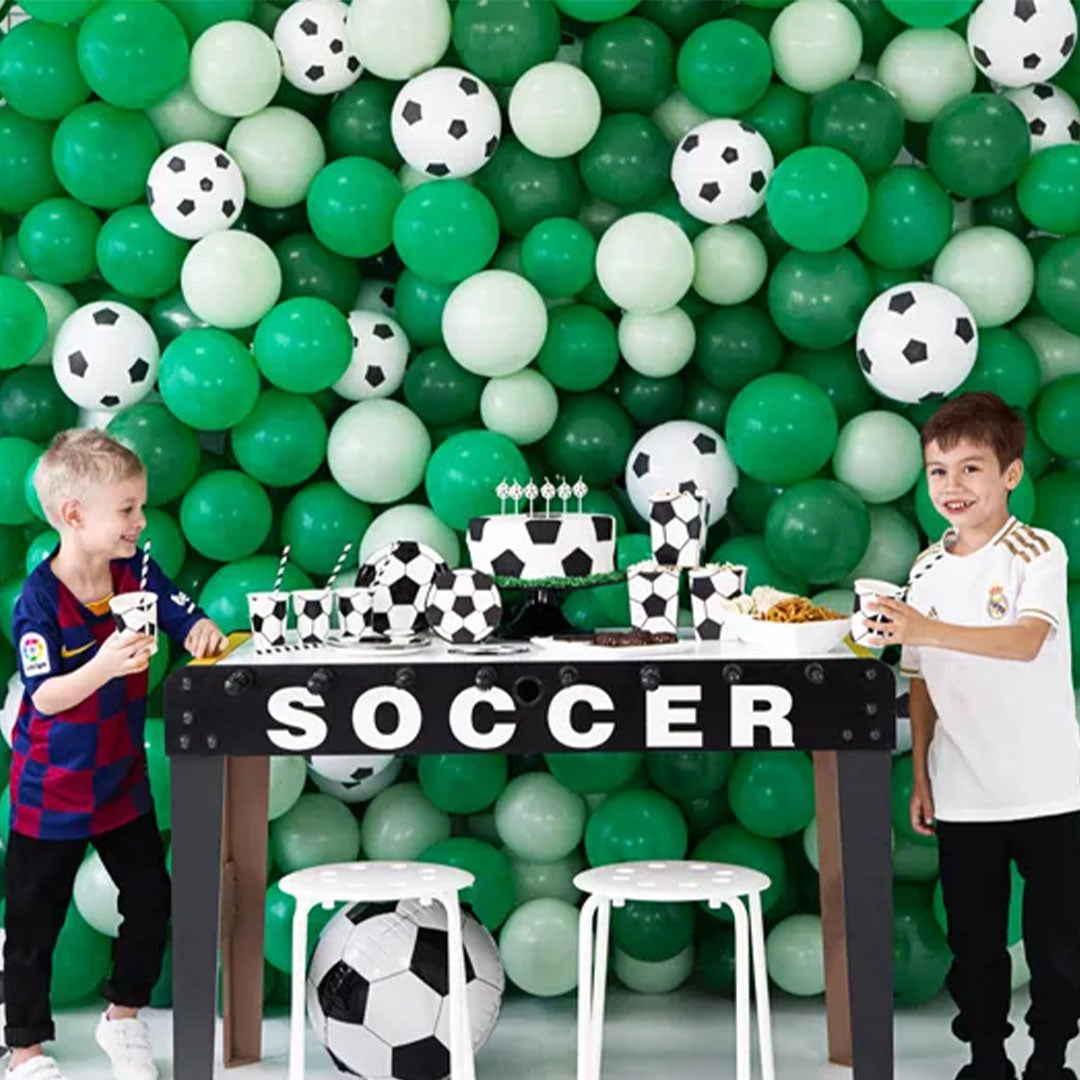 Twee jongens vieren een voetbalfeestje met groene en witte ballonnen en bijpassende tafeldecoratie.