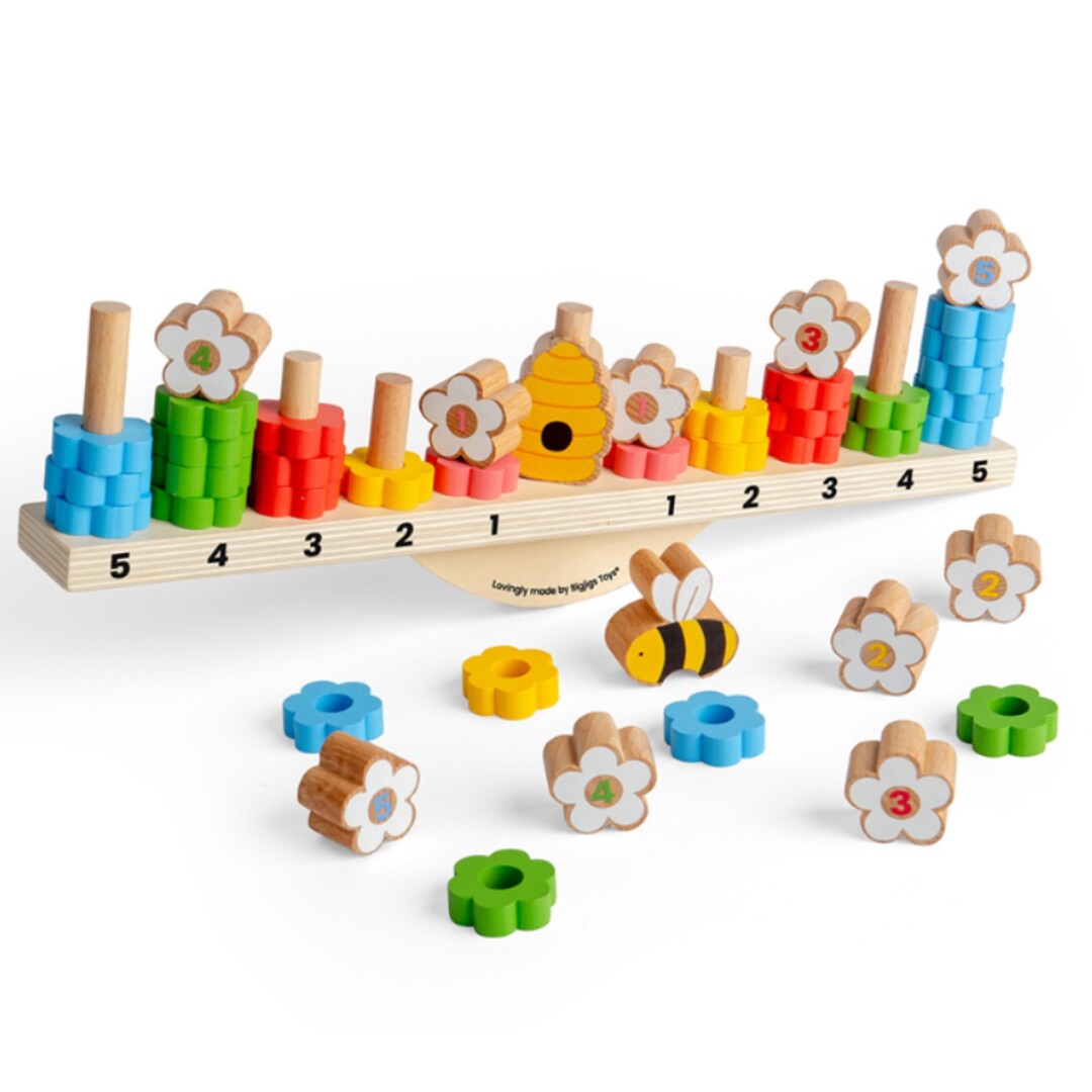 Bigjigs houten balanceerspel met bloemen, bij en gekleurde ringen, deels op de weegschaal en deels los.