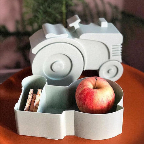 Blafere lichtgroene tractor lunchbox open met een appel en crackers.