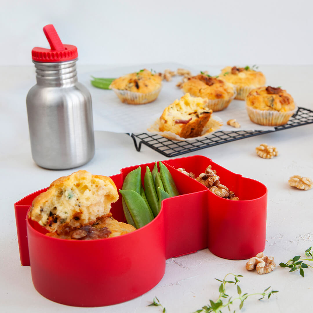 blafre rode tractor lunchbox met eten en een drinkfles op een tafel.