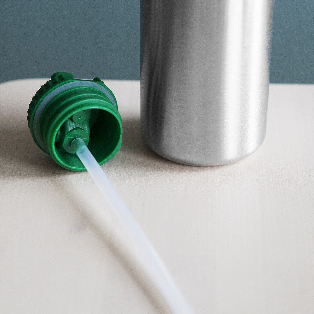 Een transparant rietje dat uit een groene drinktuit van een zilveren fles steekt.