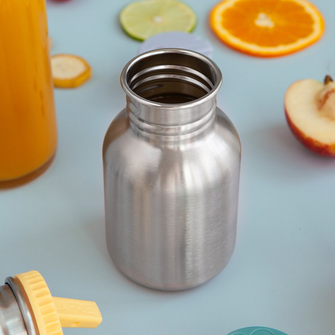 Detail van de open roestvrijstalen drinkfles, omringd door fruit en een geel rietje.