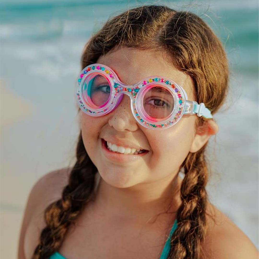 Een lachend kind draagt de bling2o zwembril Dazzle Gumball Gleam op het strand.