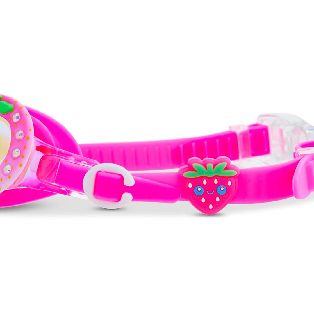 Detail van de roze band van de kinderzwembril met een klein aardbeienbedeltje.