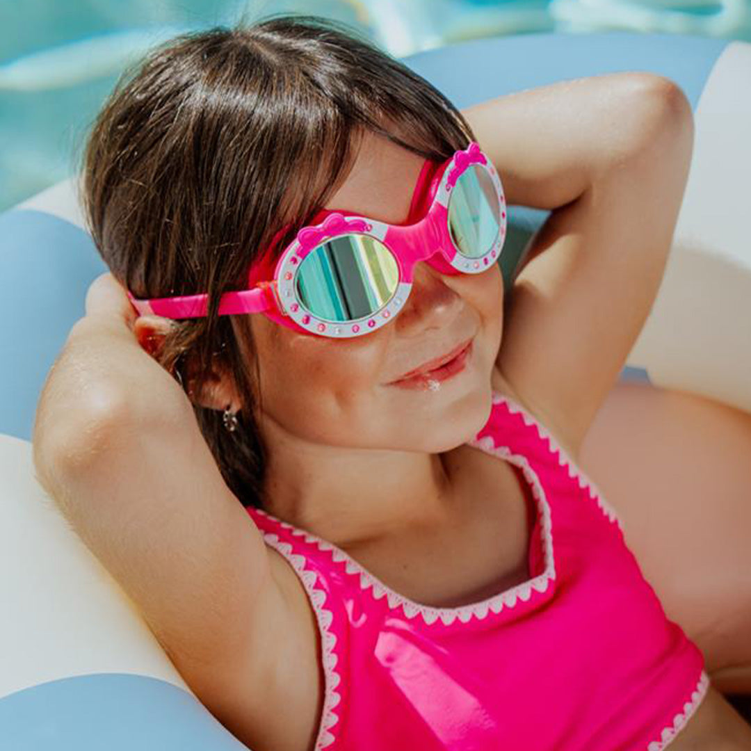 Een kind draagt de bling2o roze kinderzwembril met strikjes en glimmende steentjes in een zwembad.