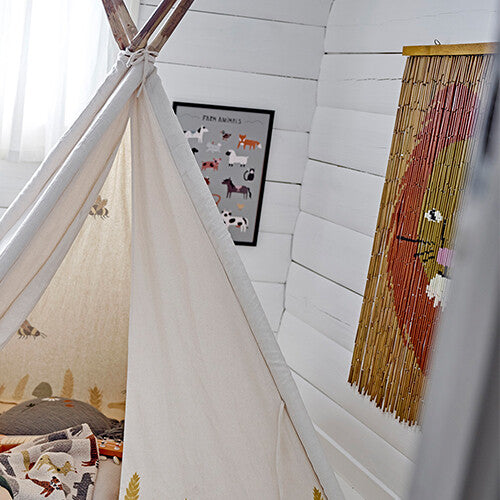 De bamboe muurdecoratie met leeuwenkop hangt aan een witte wand naast een tipi.