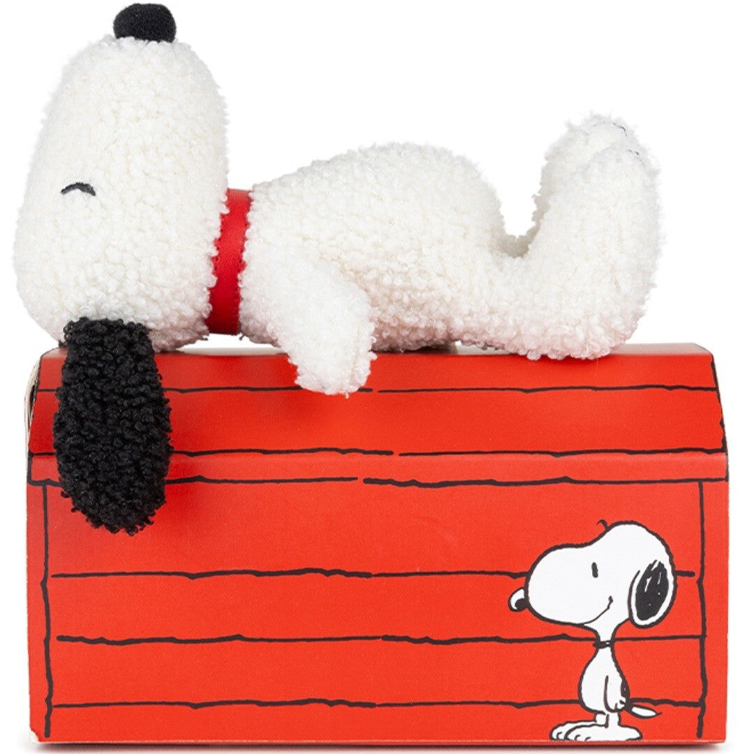 bon ton toys pluchen Snoopy knuffel ligt op een rode doos in de vorm van een hondenhok.