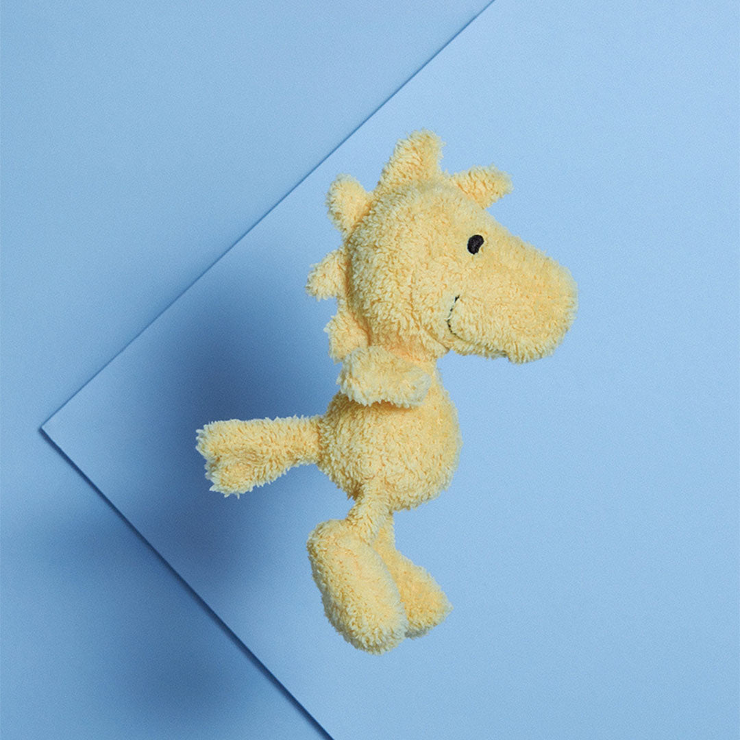 Bon Ton Toys pluchen babyspeelgoed van Woodstock, liggend op een blauwe ondergrond.