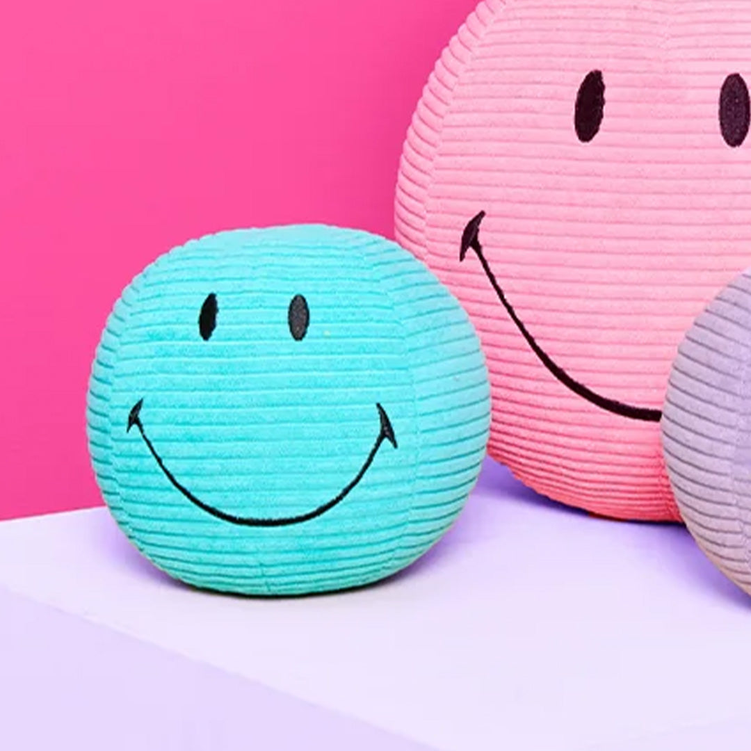 Bon ton toys blauwgroene corduroy knuffelbal met smiley gezicht, naast roze en paarse knuffelballen.
