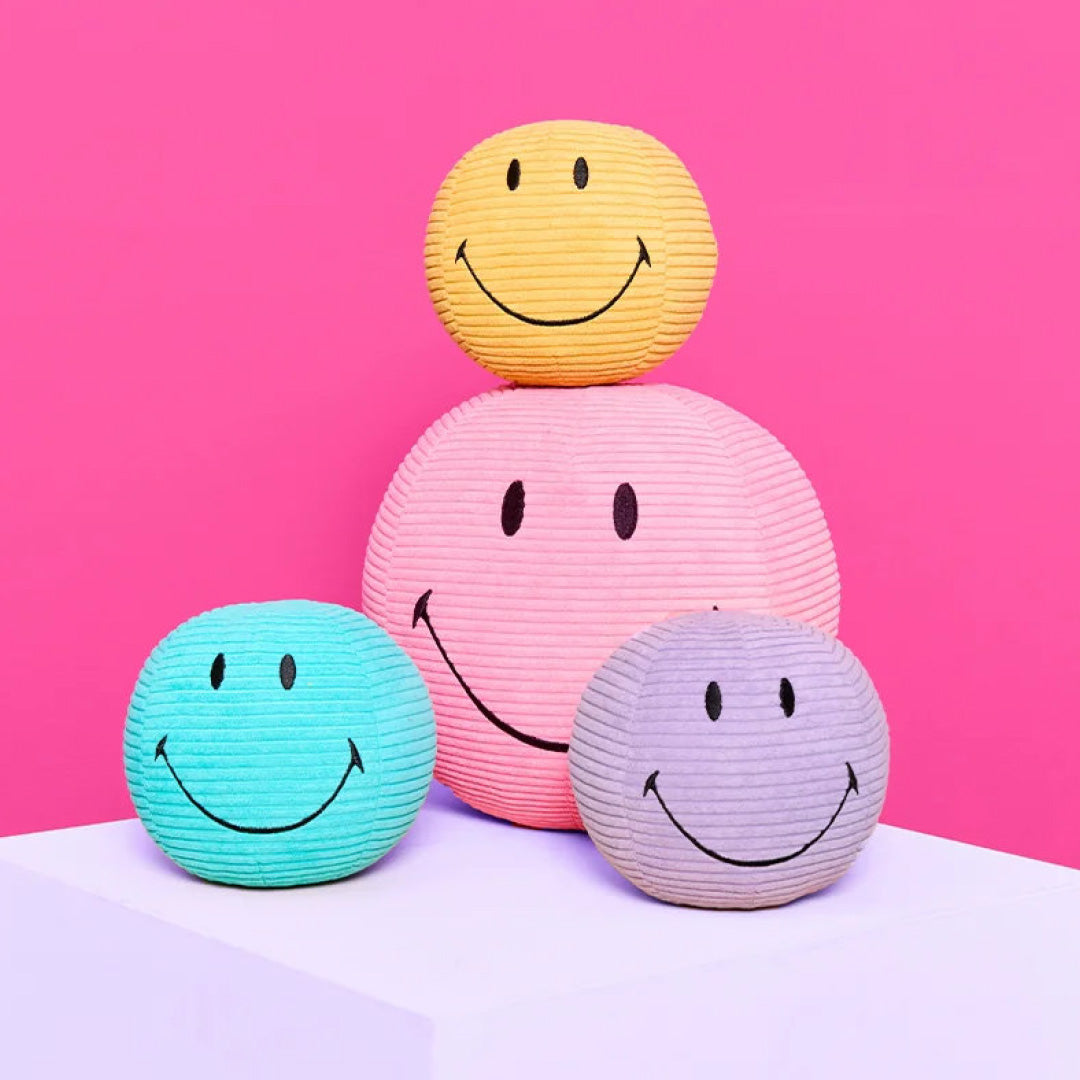 Collectie bon ton toys corduroy knuffelballen in geel, roze, blauw en paars met smileygezichten.