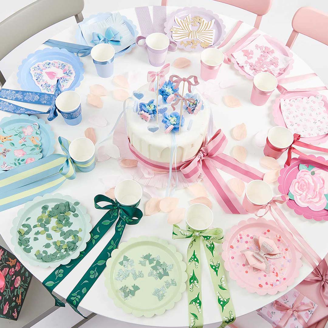 Een feestelijk gedekte tafel met Rico Design papieren borden en andere feestartikelen in pastelkleuren.