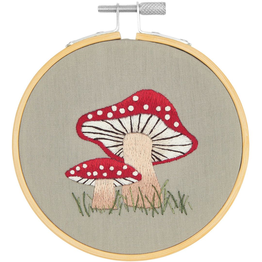 Rico Design borduurwerk van twee paddenstoelen met rode hoeden en witte stippen in een houten borduurring.