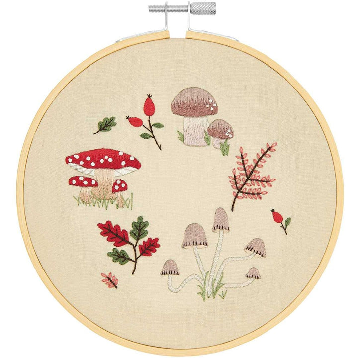 Rico Design borduurring met een geborduurde paddenstoelkrans van verschillende paddenstoelen, bladeren en bessen op beige stof.