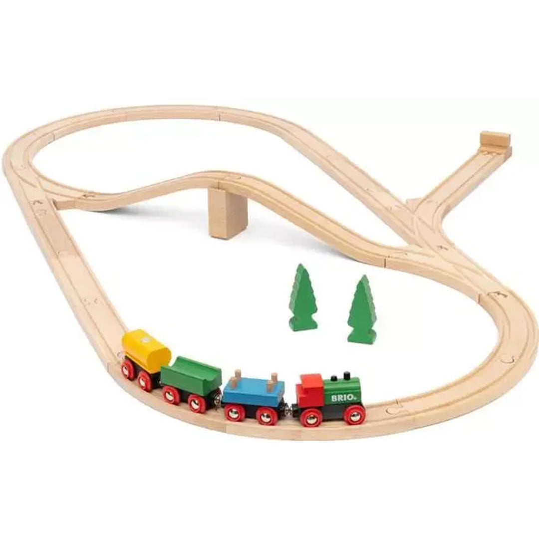 Brio houten treinbaan met een trein bestaande uit een locomotief en drie wagons, en twee groene bomen.