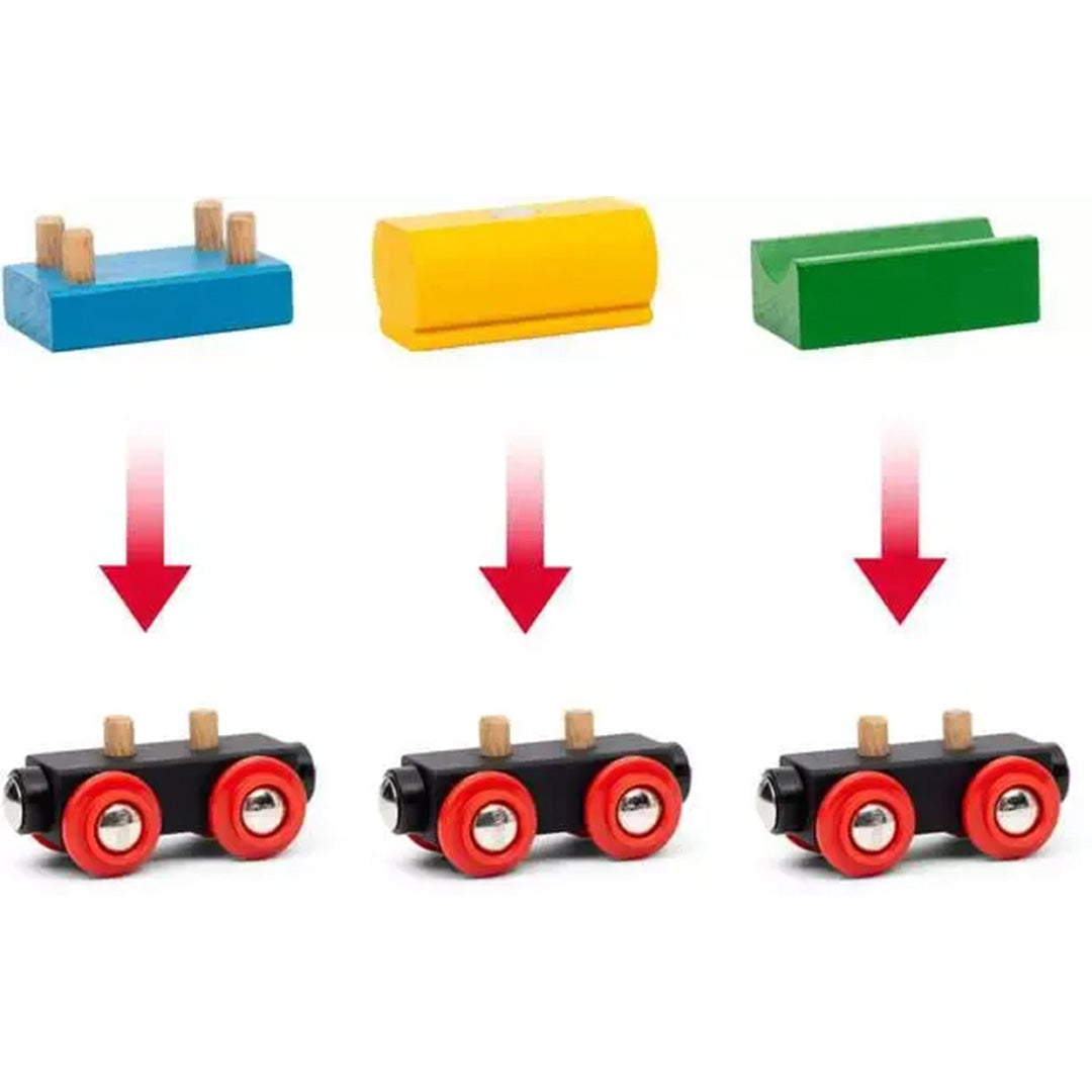 Detailfoto van drie gekleurde Brio wagonopzetstukken die op de zwarte onderstellen met rode wielen passen.