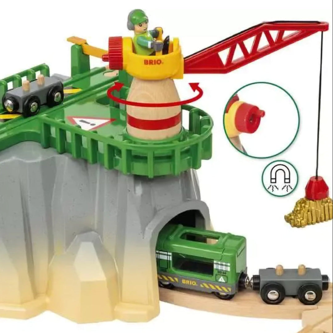 Detail van de Brio speelgoedtreinset met een kraan op een berg en een groene trein die uit een tunnel komt.