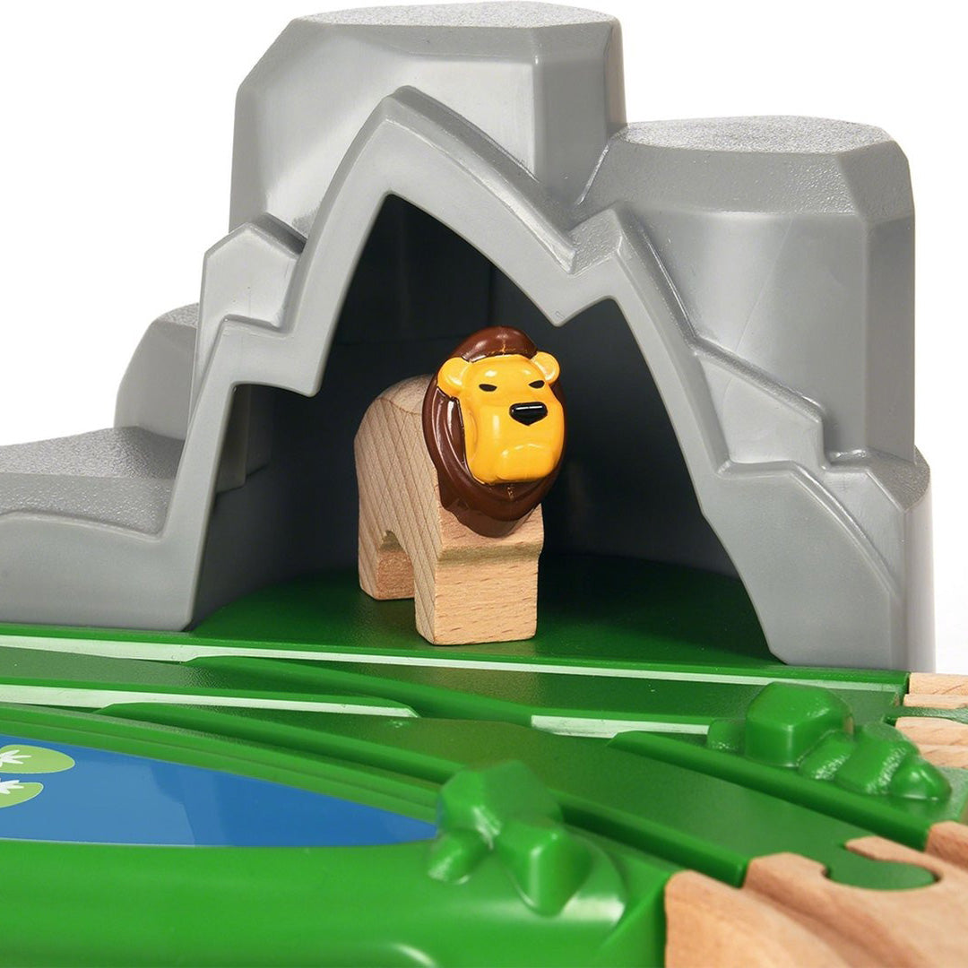 Houten leeuwfiguur in een grijze rotsgrot met een vijver.