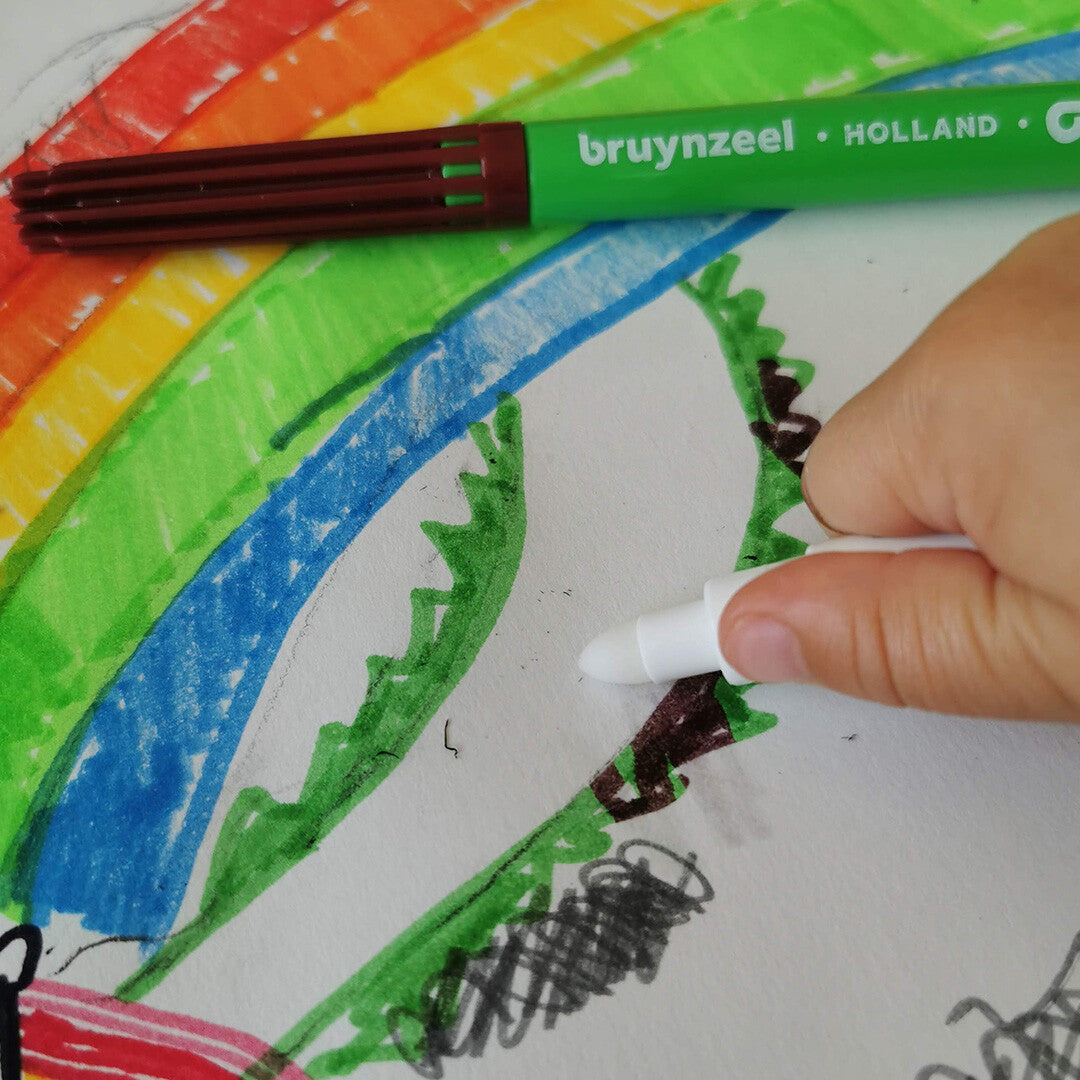 Een kinderhand die met een witte bruynzeel magische viltstift over een tekening van een regenboog kleurt.
