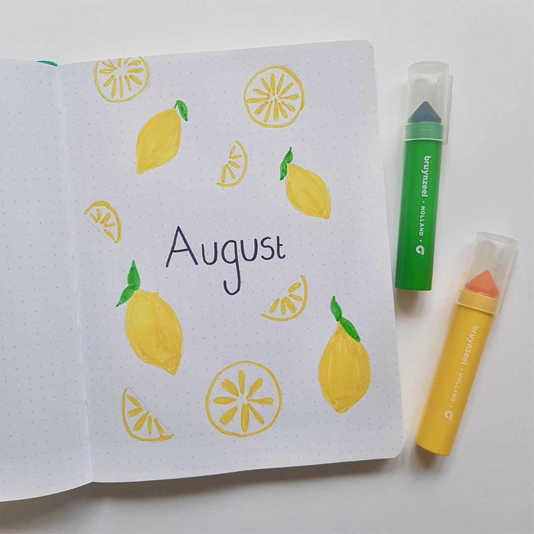 Een open notitieboekje met citroentekeningen en het woord "August", met twee Bruynzeel Kids Mega Point viltstiften ernaast.