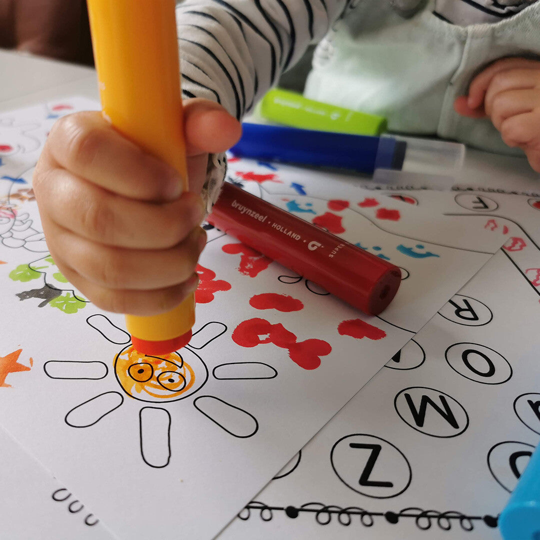Een kinderhand stempelt met een gele Bruynzeel stempelstift een zon op papier.