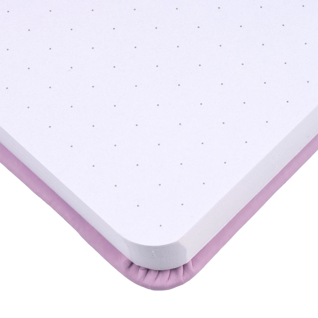 Detail van de hoek van een open lila bullet journal voor kinderen met puntjespapier.