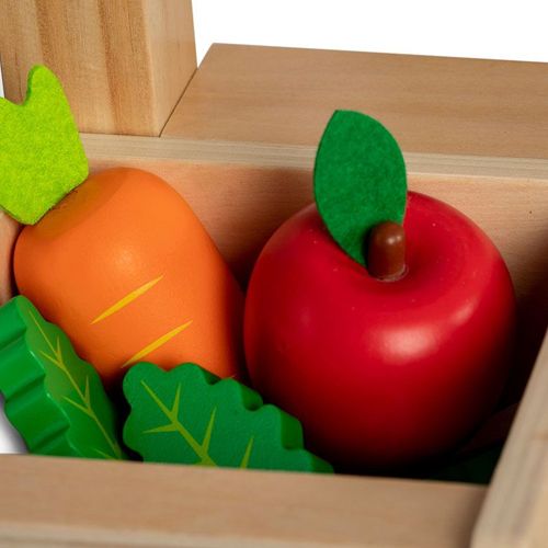 Houten speelgoedwortel, appel en bladeren in een houten kist.