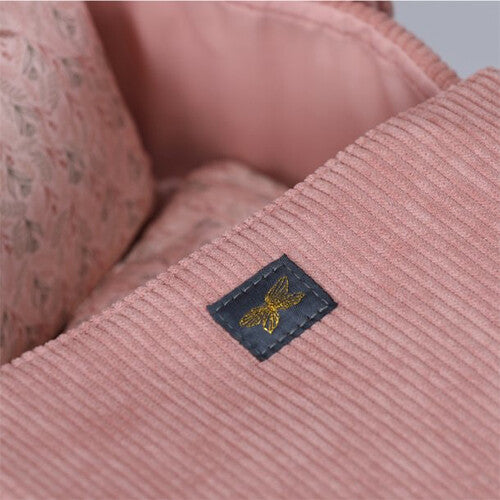 Detail van de roze corduroy stof van de poppenreiswieg met het by astrup logo.