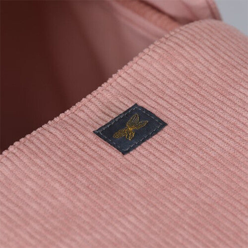 Detail van de roze corduroy by astrup poppenreiswieg met een label met bijenlogo.