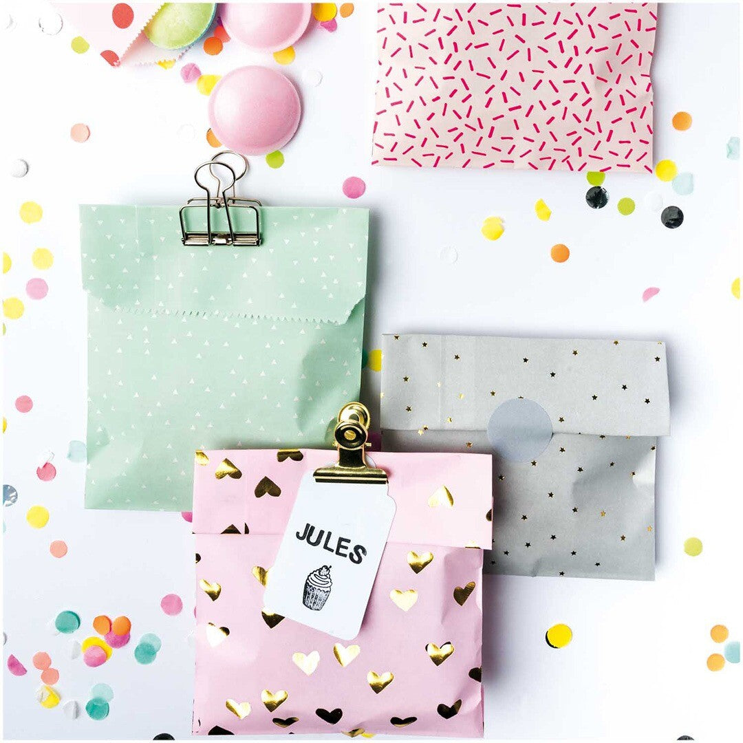 Vier open cadeauzakjes met verschillende patronen zoals harten, sterren en driehoekjes, omringd door confetti.