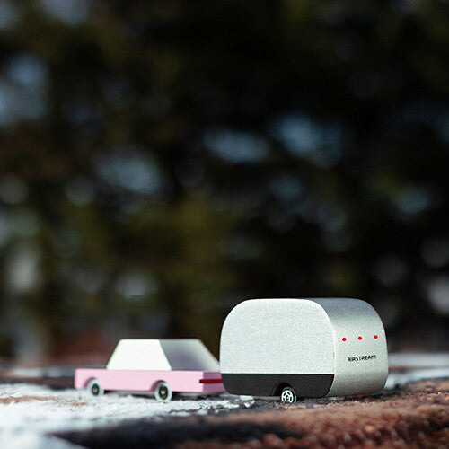 Candylab speelgoedcaravan Airstream en roze speelgoedauto in een besneeuwde buitenomgeving.