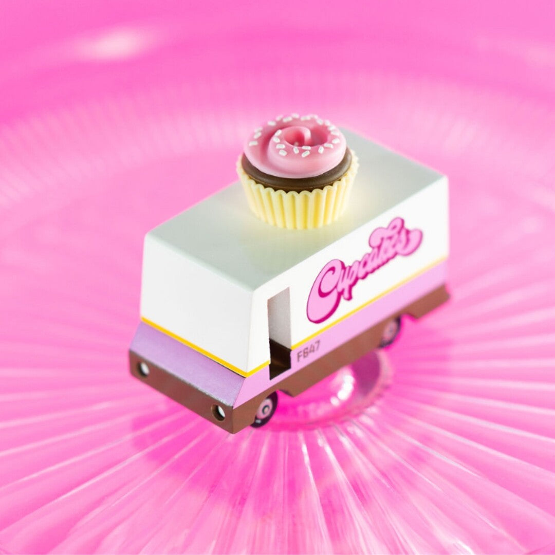 Candylab speelgoed cupcake van met een roze cupcake op het dak, schuin gefotografeerd op een roze geribbelde ondergrond.