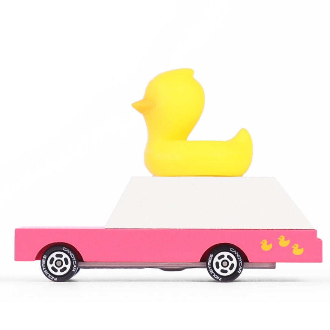 Candylab houten speelgoedauto met roze onderstel, wit dak en een gele badeend erop, van de zijkant gezien.