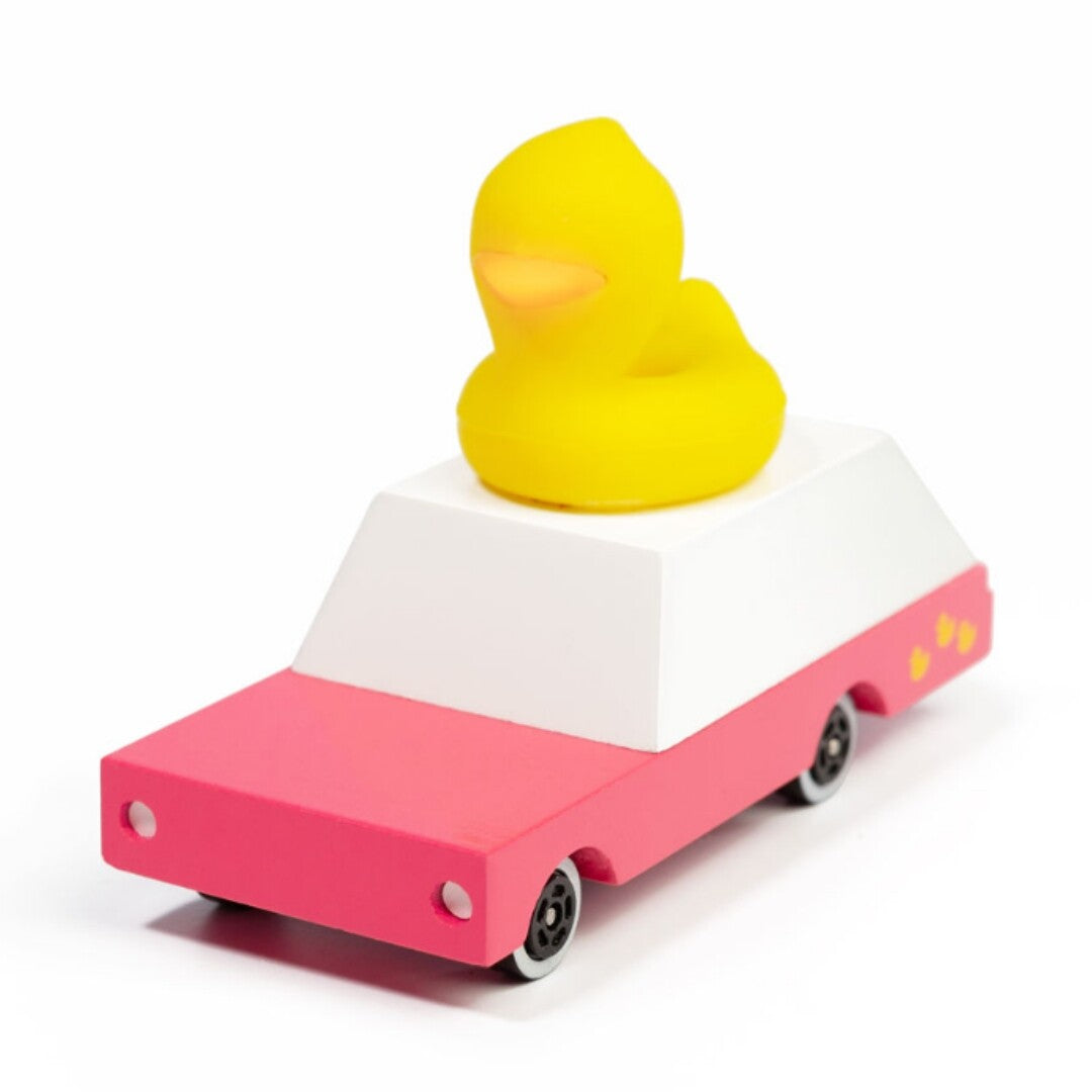 Candylab houten speelgoedauto met roze onderstel, wit dak en een gele badeend erop, schuin van voren gezien.