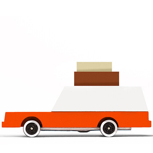Candylab houten speelgoedauto met bagage op het dak, van de zijkant gefotografeerd.