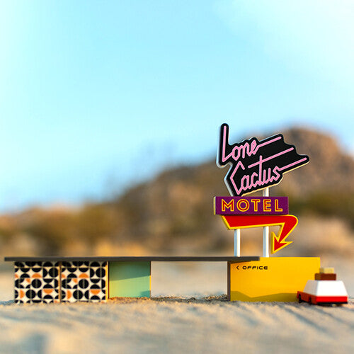 Candylab houten speelgoedauto in een woestijnlandschap met een motelbord.