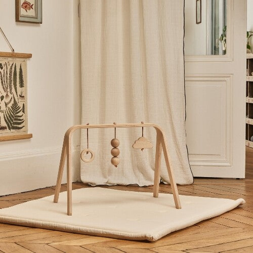 Charlie Crane houten babygym op een lichte speelmat in een kamer.